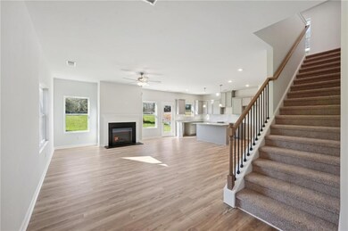 Unfurnished living room with ceiling fan, stairway, light wood-style flooring, a fireplace with flush hearth, and recessed lighting