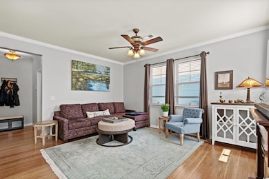 Living room with ceiling fan, light wood-style flo