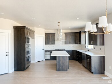 Kitchen with a kitchen island, decorative light fixtures, decorative backsplash, light wood finished floors, and recessed lighting