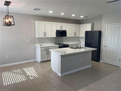 Kitchen featuring black appliances, a sink, light 