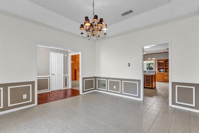 Spare room featuring light tile patterned floors, ornamental molding, a chandelier, a decorative wall, and beverage cooler