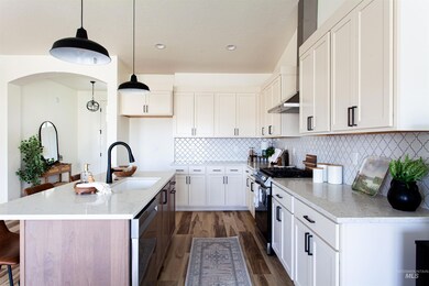 Kitchen with range with gas stovetop, dishwashing machine, wood finished floors, light stone countertops, and white cabinets