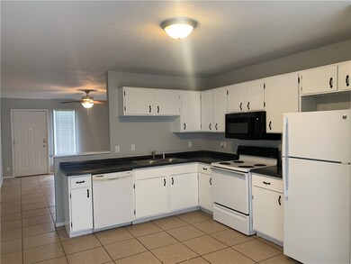 Kitchen with a sink, dark countertops, white appli