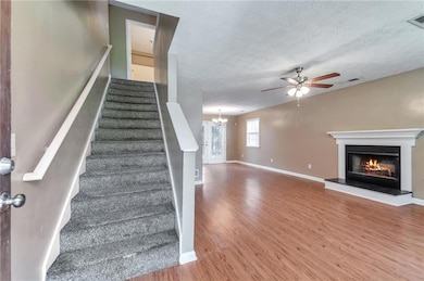 Stairway featuring wood finished floors, ceiling fan, a glass covered fireplace, baseboards, and a chandelier