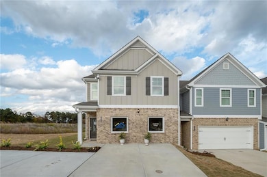 Craftsman-style home featuring board and batten siding, driveway, and brick siding