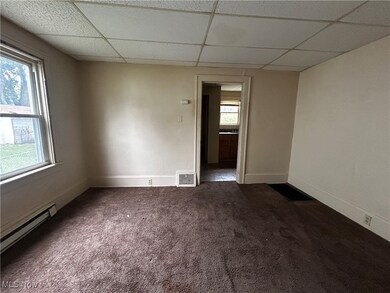Spare room with a paneled ceiling, a baseboard radiator, and dark carpet