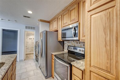 Kitchen with light stone counters, visible vents, 