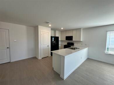 Kitchen with white cabinets, a peninsula, black appliances, light wood-type flooring, and recessed lighting