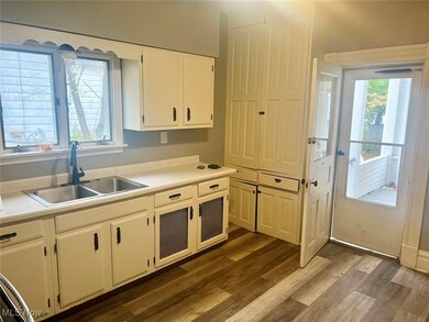 Kitchen with white cabinets, light countertops, and dark wood-style flooring