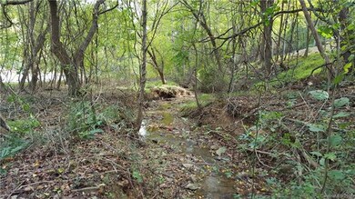 Tranquil rear yard with rushing stream runs along 