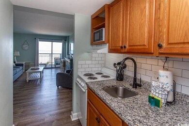 Kitchen with electric range, light stone countertops, built in microwave, range hood, and a sink