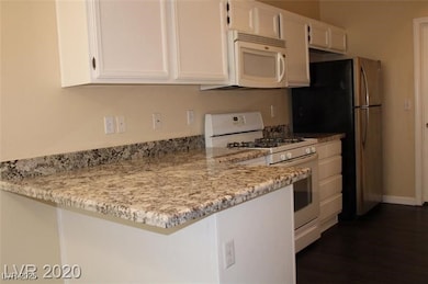 Kitchen with white appliances, a peninsula, dark w