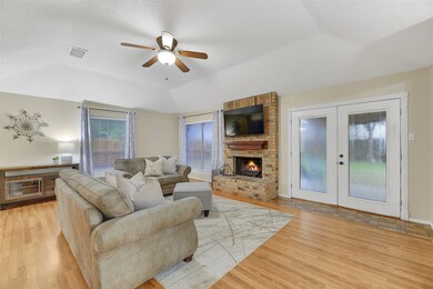 The family room is anchored by a charming wood-burning fireplace with a brick hearth flanked by sunlit windows. French doors open out to a covered back patio that overlooks the ample backyard.