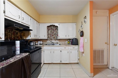 Kitchen featuring white cabinetry, black appliances, sink, and light tile patterned flooring