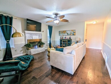 Living room with a textured ceiling, a fireplace, ceiling fan, and hardwood / wood-style floors