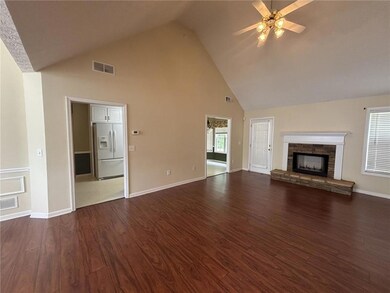 Unfurnished living room featuring high vaulted ceiling, ceiling fan, a stone fireplace, dark wood finished floors, and baseboards