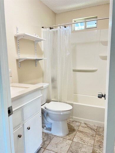 Full bathroom with vanity, shower / bath combo with shower curtain, and a textured ceiling