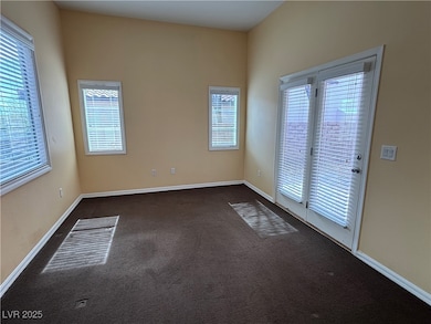 Unfurnished room with baseboards and dark carpet