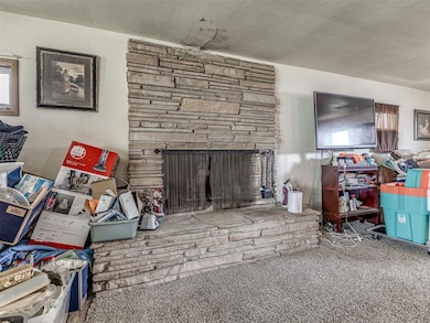 Carpeted living room featuring a stone fireplace