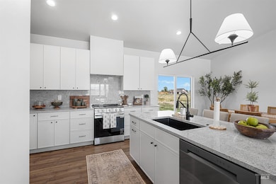 Kitchen with stainless steel gas range, dishwashing machine, dark wood-type flooring, decorative backsplash, and light stone countertops