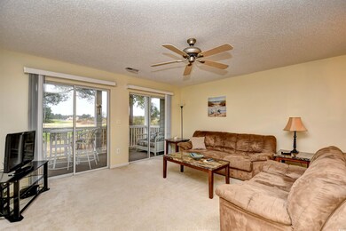 Living room featuring ceiling fan, light colored carpet, and a textured ceiling