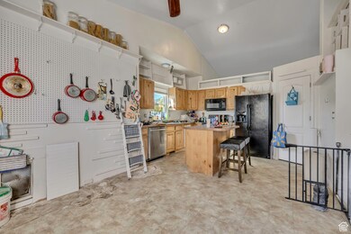 Kitchen featuring black appliances, a breakfast bar area, light countertops, a kitchen island, and lofted ceiling