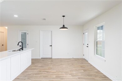 Kitchen featuring light wood-style flooring, hanging light fixtures, light countertops, white cabinets, and recessed lighting
