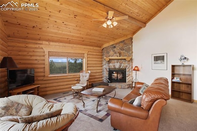 Living area featuring wood ceiling, carpet flooring, ceiling fan, a fireplace, and rustic walls