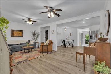Living area with ornamental molding, ceiling fan, and wood finished floors