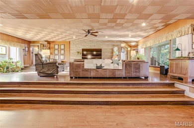 Living area with light wood-type flooring, wooden walls, a ceiling fan, and recessed lighting