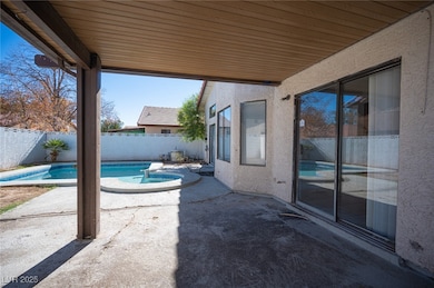 Fenced backyard featuring a patio and a pool with connected hot tub
