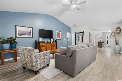 Living room with vaulted ceiling, ceiling fan, and