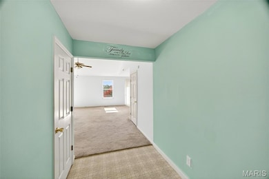 Hallway featuring light colored carpet and baseboards