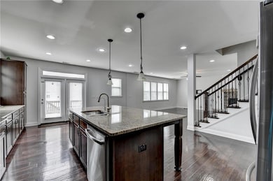 Kitchen with dark brown cabinetry, stainless steel appliances, dark wood-style floors, and a sink