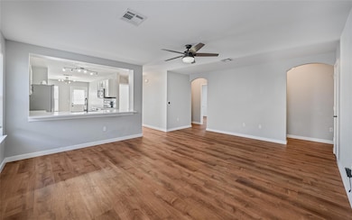 Unfurnished living room featuring dark wood-type flooring, ceiling fan, and a chandelier