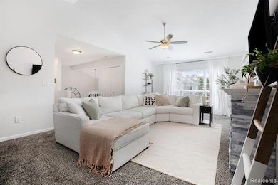 Carpeted living area featuring baseboards and a ceiling fan