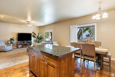 Kitchen featuring brown cabinets, open floor plan, hanging light fixtures, light wood finished floors, and a kitchen island