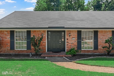 Property entrance featuring a lawn, roof with shingles, and brick siding