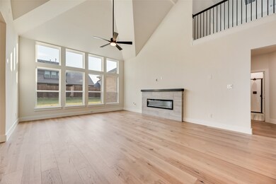Unfurnished living room featuring high vaulted ceiling, a fireplace, light wood-style flooring, and ceiling fan