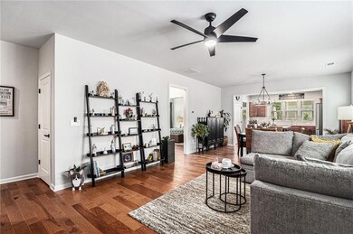Living area featuring a ceiling fan, dark wood-style flooring, and baseboards