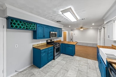Kitchen with a peninsula, blue cabinetry, crown molding, appliances with stainless steel finishes, and a textured ceiling