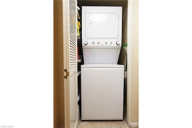 Washroom with light tile patterned floors and estacked washer and dryer