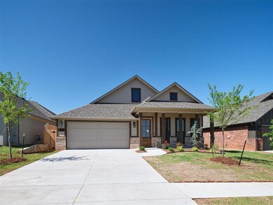View of front of house featuring an attached garage, driveway, brick siding, and a porch