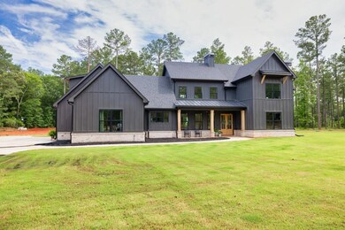 View of front of house with board and batten siding, a front yard, a shingled roof, a chimney, and a standing seam roof