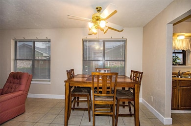 Tiled dining space with sink and ceiling fan