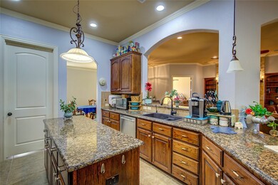 Kitchen featuring crown molding, pendant light fixtures, a center island, dark stone counters, and recessed lighting