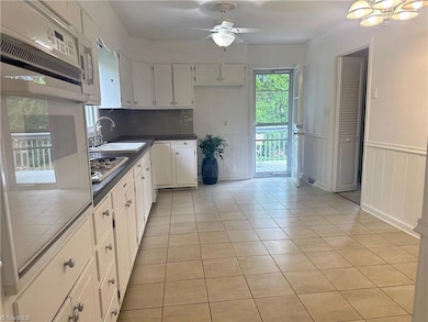 Large kitchen with eat in area and door to back deck. Doorway on the right leads to the den