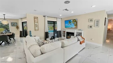 Living room featuring light marble finish flooring, a glass covered fireplace, and recessed lighting