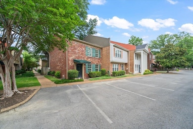 View of property with uncovered parking and brick siding