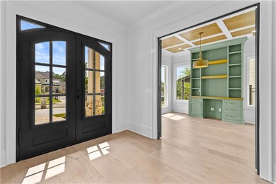 Entryway featuring french doors, light wood-type flooring, crown molding, and baseboards